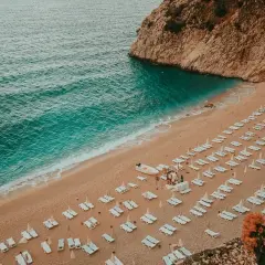 Piękna plaża z rzędami leżaków i turkusową wodą. Idealne miejsce, by zastanowić się, gdzie do Turcji na wakacje.