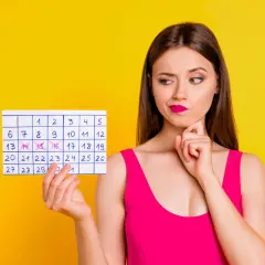 Zastanawiasz się, jak przyspieszyć okres? Kobieta z kalendarzem w ręku analizuje daty, szukając rozwiązania.