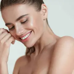 Donna sorridente con pelle luminosa, un esempio di come mantenere la pelle giovane e radiosa.