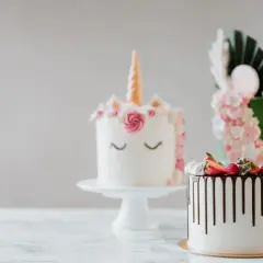 Tre fantasifulla tårtor står uppradade, redo för morgondagens firande. En enhörning, en grön med blommor och en med choklad och bär. Tårta dagen innan är alltid spännande!
