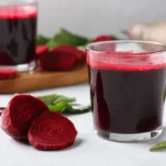 Szklanka z buraczanym zakwasem, na wierzchu piana. Obok plastry buraka i liście.