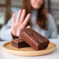 Kobieta odrzuca brownie, wybierając dietę bez cukru.