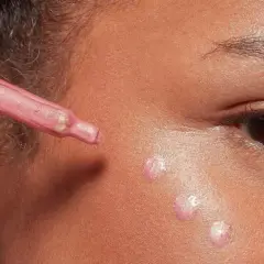 Applicazione di illuminante liquido sul viso con contagocce per un look radioso.