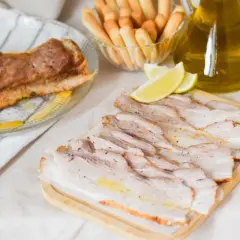 Chicharrón de Cádiz, crujiente y jugoso, servido con limones y palitos de pan.