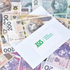 Zasiłki przedemerytalne po nowemu: koperta ZUS na stosie polskich banknotów 200 zł.