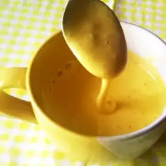 Gęsty, żółty kogel mogel spływa z łyżki do kubka. Idealny przepis na szybki deser.