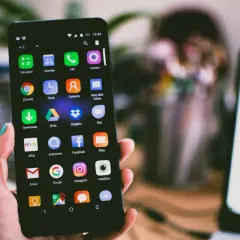Dłoń trzyma smartfon z ikonami aplikacji. Jeśli masz problem, jak zresetować zablokowany telefon, ten ekran może pomóc.
