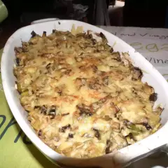 Un plat gratiné de croziflette avec des morceaux de saucisse de Morteau, prêt à être dégusté.
