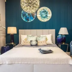 Eleganckie lustro nad łóżkiem w sypialni, ozdobione złotą ramą, dodaje blasku i stylu.