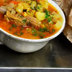 Gęsta, aromatyczna zupa na żeberkach z ziemniakami i marchewką, posypana świeżym koperkiem.