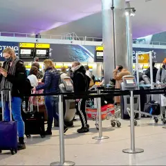 Kolejka do odprawy na lotnisku. Ludzie z bagażami czekają na swoją kolej, by nadać paczkę do UK.