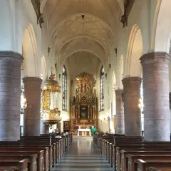 Interiör av St Jacobs kyrka med bänkar, pelare och altare.