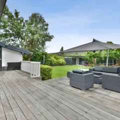 Aménagement coin détente extérieur avec salon de jardin gris sous un grand parasol, sur une terrasse en bois.