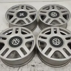 Cztery srebrne felgi aluminiowe Volkswagen z czarnym środkiem i logo VW.