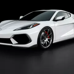 Biały Chevrolet Corvette c8, sportowy samochód o aerodynamicznej sylwetce, prezentuje się na czarnym tle.