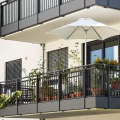 Nowoczesny balkon w bloku z roślinami w doniczkach i białym parasolem. Inspiracja, jak wykończyć balkon w bloku, by był funkcjonalny i estetyczny.