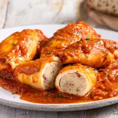 Calamari ripieni in padella, soffocati in un sugo rosso saporito, con un ripieno visibile e prelibato.