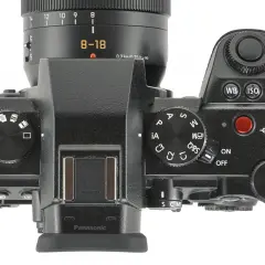 Górna część aparatu Panasonic Lumix G9 II z obiektywem 8-18 mm. Widoczne pokrętła trybów, przyciski i ekran.