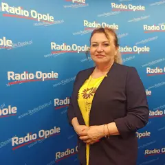 Kobieta w żółtej bluzce i granatowej marynarce na tle z logo Radia Opole.