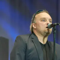 Wojciech Cugowski śpiewający do mikrofonu w czarnej marynarce.