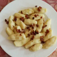 Kopytka z boczkiem, jak u babci. Pyszne ciasto na kopytka przepis babci, podane na białym talerzu.