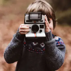 Dziecko z aparatem Polaroid Land Camera, gotowe do uchwycenia magicznych chwil.