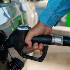 Dłoń trzymająca pistolet paliwowy przy samochodzie. Czas na zimowe paliwo od kiedy? Przygotuj auto na mrozy.