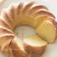 Una soffice torta di ricotta, spolverata di zucchero a velo, con una fetta tagliata che ne rivela la morbidezza.