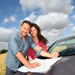 Para, planując ubezpieczenie samochodu na wyjazd, z mapą w ręku, cieszy się podróżą.