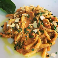 Busiate alla trapanese, un piatto di pasta siciliana con un sugo ricco, guarnito con mandorle a lamelle e prezzemolo fresco.