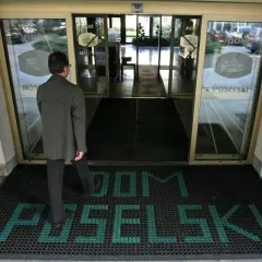 Mężczyzna wchodzi do hotelu poselskiego. Na wycieraczce przed wejściem widnieje napis "DOM POSELŚKI".