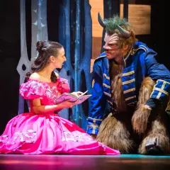 Piękna Bella w różowej sukni czyta Bestii z poznańskiego Teatru Muzycznego. Sprawdź repertuar!