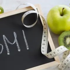 Tablica z napisem BMI, miarka krawiecka i świeże owoce. Zastanawiasz się, ile powinnaś ważyć w ciąży?