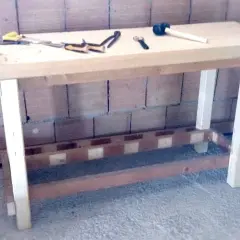 Un banco da lavoro in legno, pronto per iniziare a fare un tavolo in legno. Attrezzi come morsa, martello e pinze sono pronti all'uso.