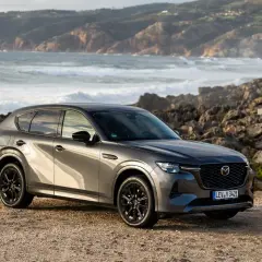 Szary SUV Mazda CX-60 na tle skalistego wybrzeża. To jeden z rodzajów hybryd, który łączy moc z ekologią.