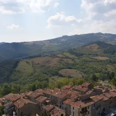 Panoramica di un borgo con tetti in cotto e colline verdi. Un assaggio di cosa vedere sul Monte Amiata, tra natura e storia.