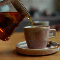 Ciemna czarna herbata nalewana do filiżanki. Osoby z refluksem powinny uważać na ten napój.