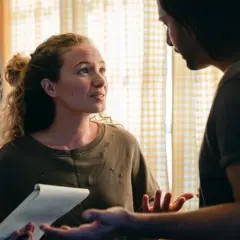 Pareja discutiendo papeles, quizás sobre una novación hipoteca. Ella sostiene un bloc de notas, él gesticula.