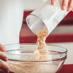 Wsypywanie mąki z przezroczystego pojemnika do szklanej miski.