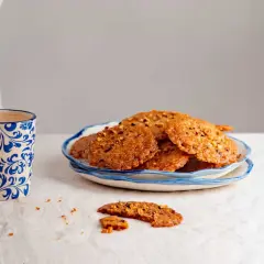 Deliciosas galletas de jengibre crujientes con trozos de nueces, servidas en un plato azul y blanco.