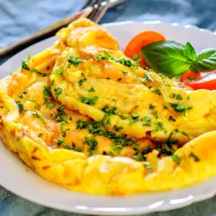 Une omelette dorée et moelleuse, garnie de persil frais. Une recette simple et rapide pour un repas savoureux.