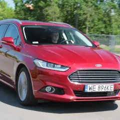 Czerwony Ford Mondeo MK4 kombi w ruchu drogowym. Kierowca uśmiecha się, a opinie o tym modelu są zazwyczaj pozytywne.
