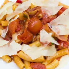 Piatto di rigatoni conditi con un ricco sugo amatriciana, pomodorini, guanciale e scaglie di pecorino.