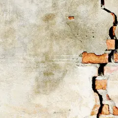 Crepe intonaco interno rivela mattoni rossi. La parete mostra segni del tempo e usura.