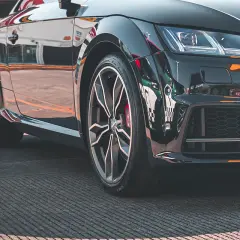 Błyszczące, czarne auto sportowe z felgami i widocznym rantem ochronnym opony.