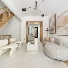 A living room showcasing minimalist interior design with a sculptural white sofa, a marble coffee table, and abstract art.