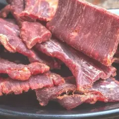 Suszone plastry mięsa wołowego na czarnym talerzu. Idealne do przekąski, gdy szukasz prostego beef jerky przepis.