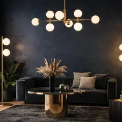 Elegante salón con lámparas bombillas decorativas doradas, sofá oscuro y mesa de centro dorada.