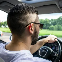 Mężczyzna w okularach prowadzi samochód, myśląc o tym, że zabrane prawo jazdy za alkohol to poważna sprawa.