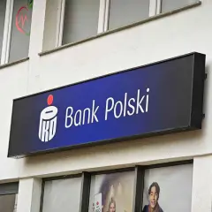Logo Banku Polskiego na niebieskim tle. Obok widoczny czerwony sygnalizator. W tle okna z grafikami, być może ankieta AML.